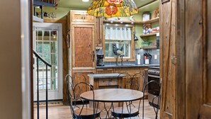 A kitchen with wooden cabinets, a round dining table, and chairs. - Jim Thorpe Rustic Cabin With Hot Tub, EV Charger, BBQ Grill & Outdoor Games! (Jim Thorpe)