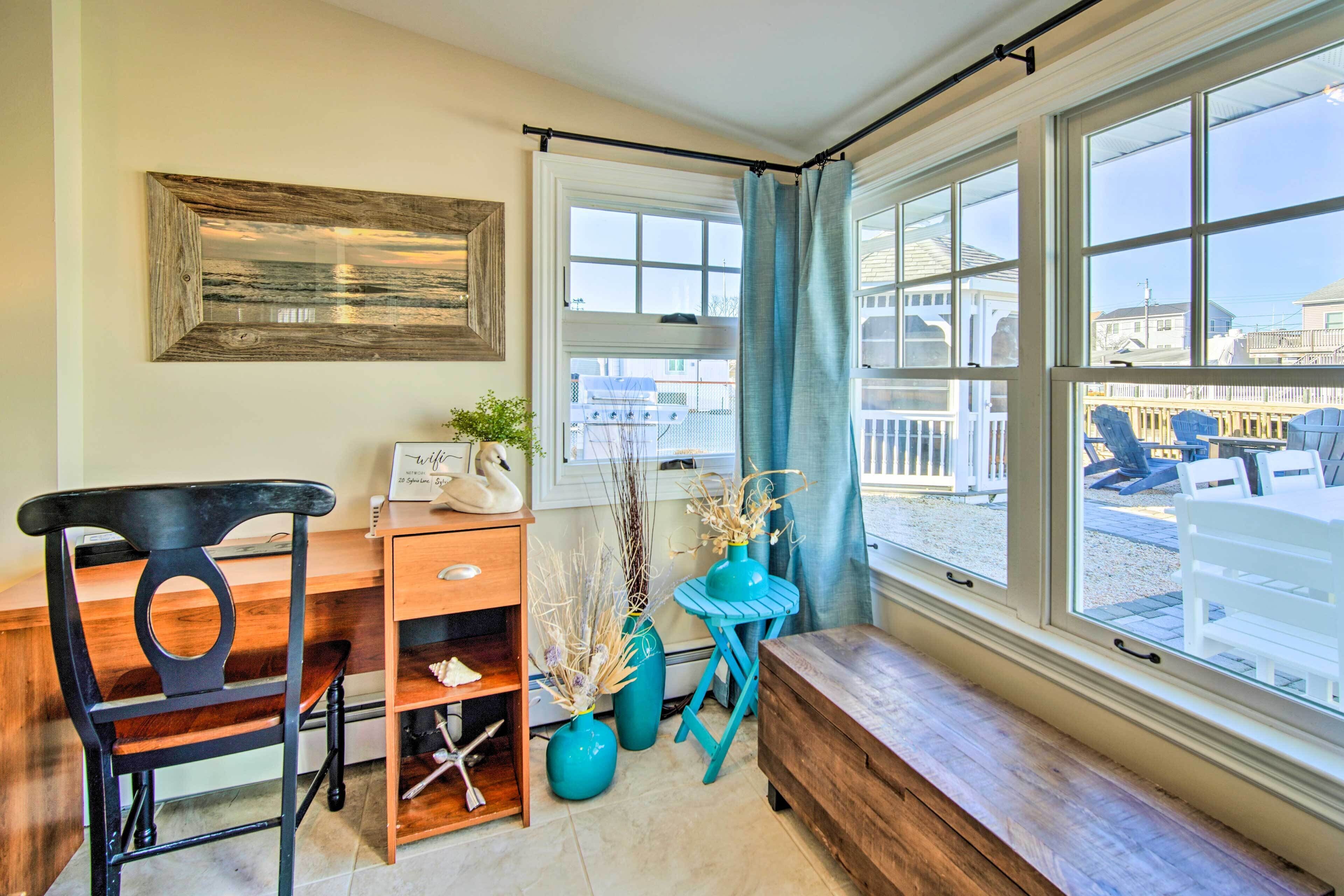 A room with a wooden desk, a chair, a bench, and a large window with a view of the outside.