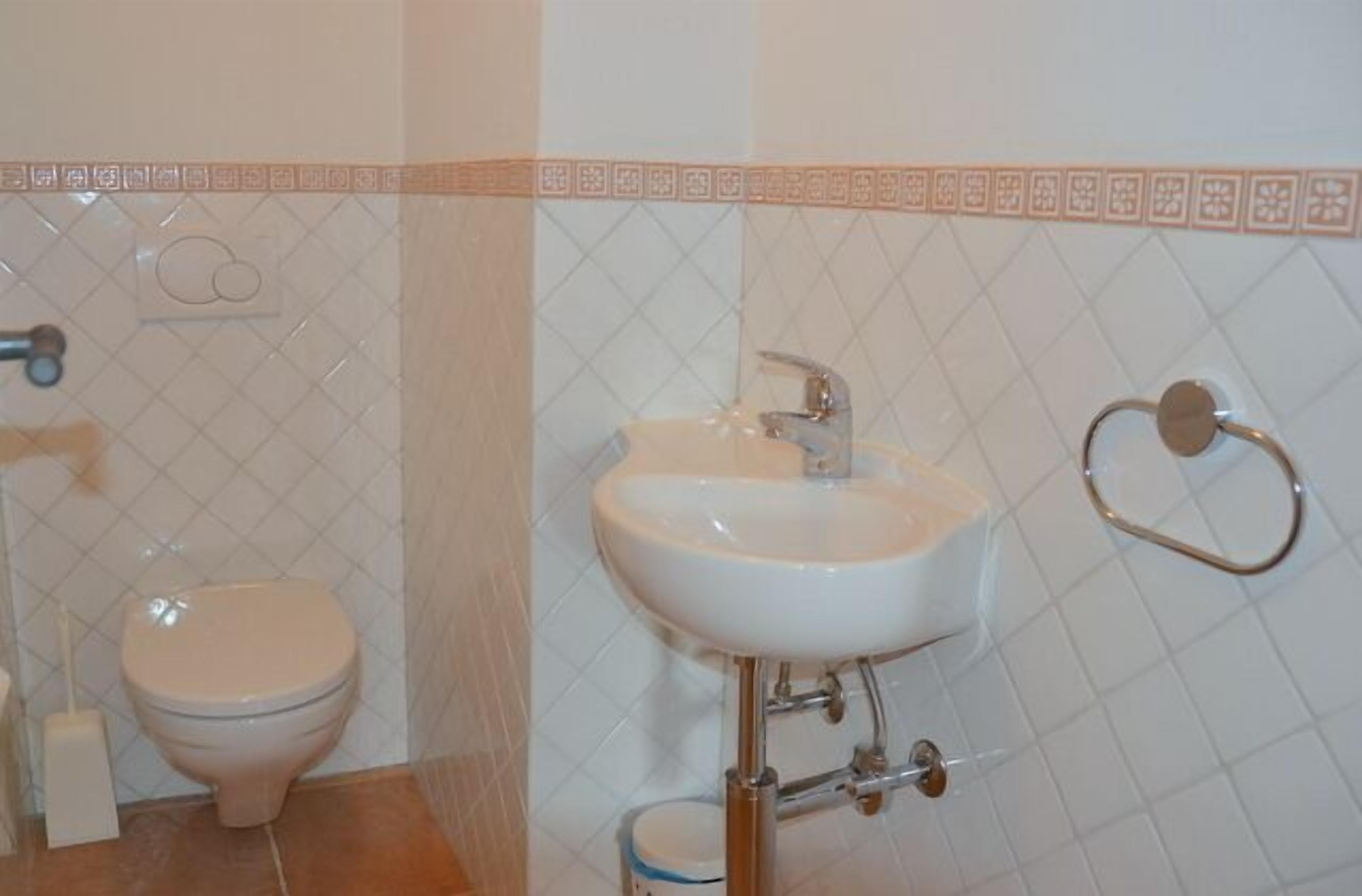 A bathroom with a toilet, sink, and towel rack.
