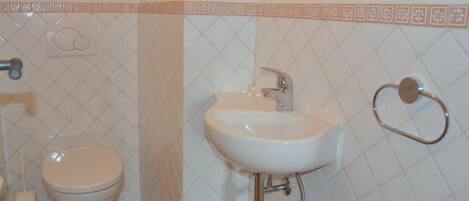A bathroom with a toilet, sink, and towel rack.