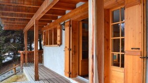 Una terraza de madera con un porche cubierto, puertas de madera y una ventana.