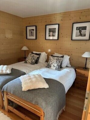 A double bed with a wooden headboard, two bedside tables with lamps, and framed pictures on the wall. - Outside: apartment on the ground floor of a chalet, for 4 people, terrace with garden furniture, acc (St-Luc)