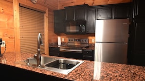 A kitchen with granite countertops, stainless steel appliances, and wooden cabinetry. - SMOKY MOUNTAIN HIGH GETAWAY (Sevierville)