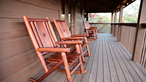 A wooden deck with rocking chairs aligned against a wooden wall. - SMOKY MOUNTAIN HIGH GETAWAY (Sevierville)