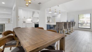 A spacious kitchen with white cabinetry, a wooden dining table, and pendant lighting. - ⚓Luxury pool home with lakefront view just minutes from the beach!⚓ (Bradenton)