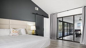 A modern hotel room with a large bed, a nightstand with a lamp, and a view of a pool through a sliding glass door. - ⚓Luxury pool home with lakefront view just minutes from the beach!⚓ (Bradenton)