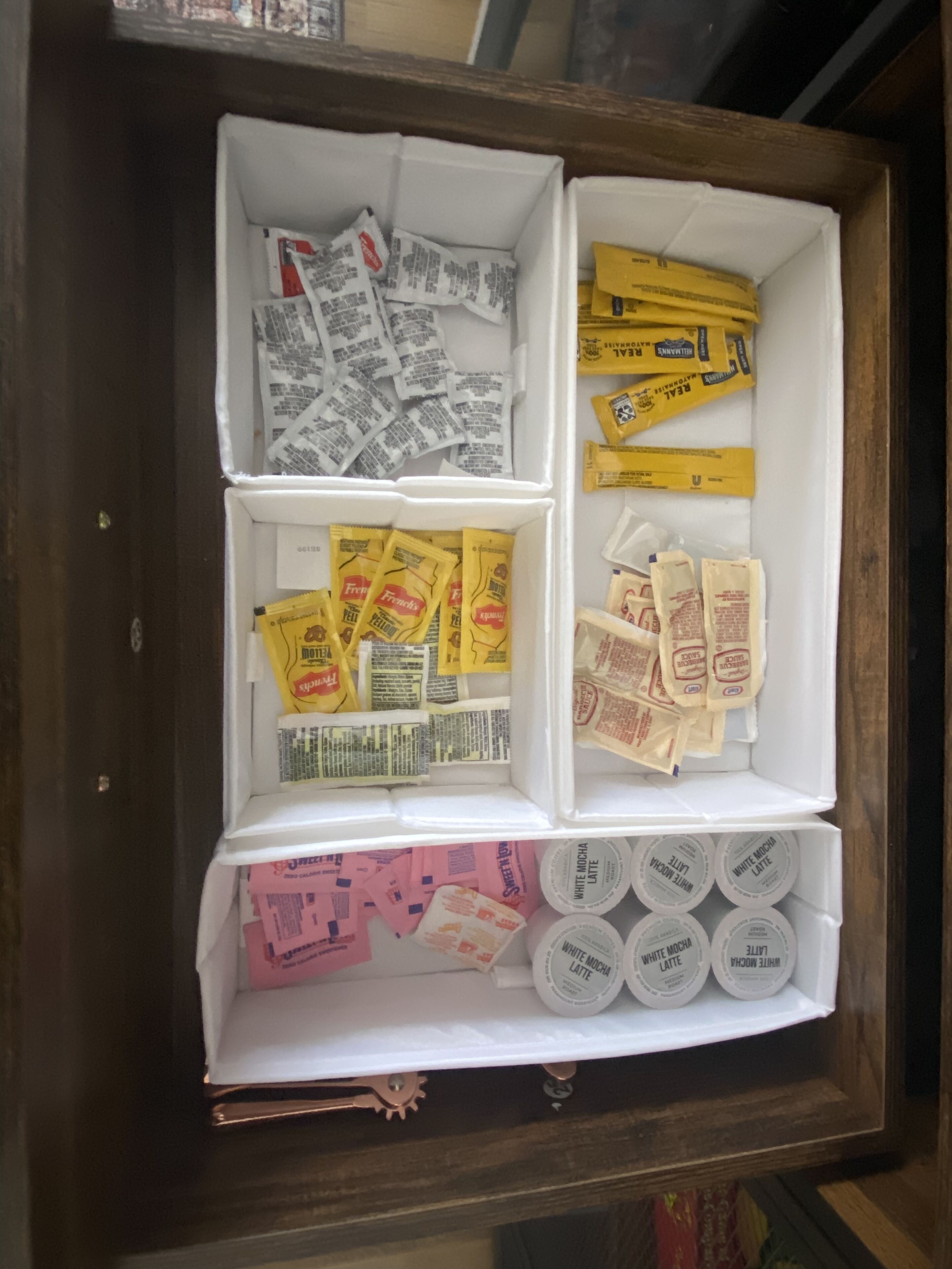 A drawer with compartments containing various food items and packets.