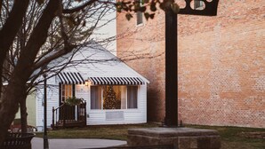 A brick building with a clock, a bench, and a covered area with a Christmas tree.