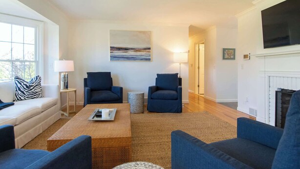 A living room with a sofa, two armchairs, a coffee table, a fireplace, and a painting on the wall. - Gorgeous Home with Game Room Dog Welcome! (Chatham)