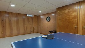 A room with a ping pong table, a dartboard, and wooden panel walls. - Gorgeous Home with Game Room Dog Welcome! (Chatham)