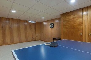 A room with a ping pong table, a dartboard, and wooden panel walls. - Gorgeous Home with Game Room Dog Welcome! (Chatham)