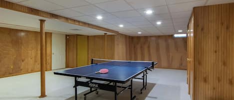 Ein Tischtennis-Tisch in einem Raum mit Holzvertäfelung und Teppichboden.
