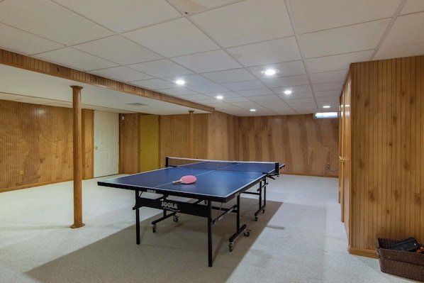 A ping pong table in a room with wooden paneling and a carpeted floor.