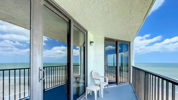 Ein Balkon mit Blick auf den Strand, ein Stuhl und ein Tisch.
