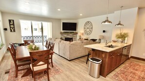 A spacious living area with a fireplace, a dining table with chairs, a sofa, and a kitchen with a sink and countertop. - Silverpine Gem - Downtown - Walk to shops, restaurants, Payette Lake - WiFi (McCall)