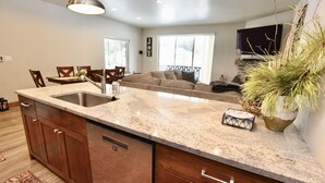 A kitchen with a granite countertop, wooden cabinets, and a built-in dishwasher. - Silverpine Gem - Downtown - Walk to shops, restaurants, Payette Lake - WiFi (McCall)