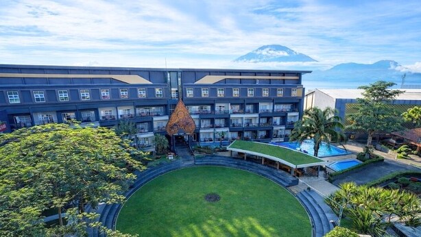 Un hotel con patio central, varios balcones y vista a la montaña.