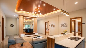 Una sala de estar moderna con sofá, mesa de centro y televisor. Cuenta con una cocina con encimera y lavamanos.
