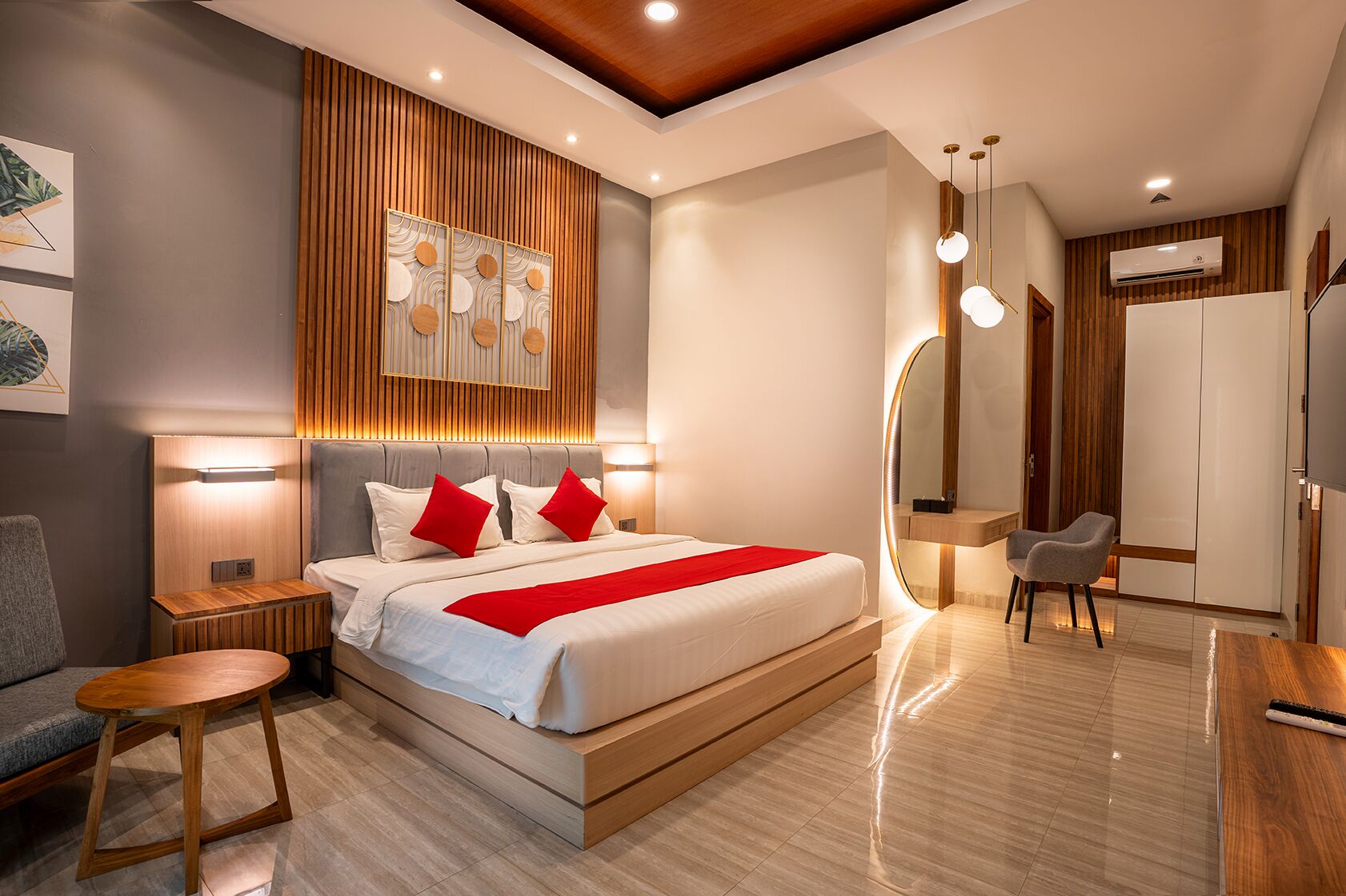 Ein modernes Hotelzimmer mit einem großen Bett, einem Nachttisch, einem Sessel, einem Schreibtisch und einem Kleiderschrank.