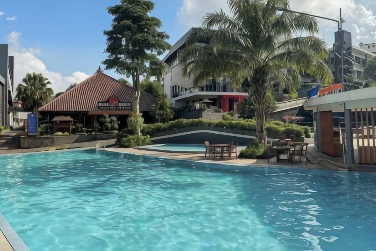 Una piscina con sillas de descanso, un restaurante y un edificio con techo rojo.