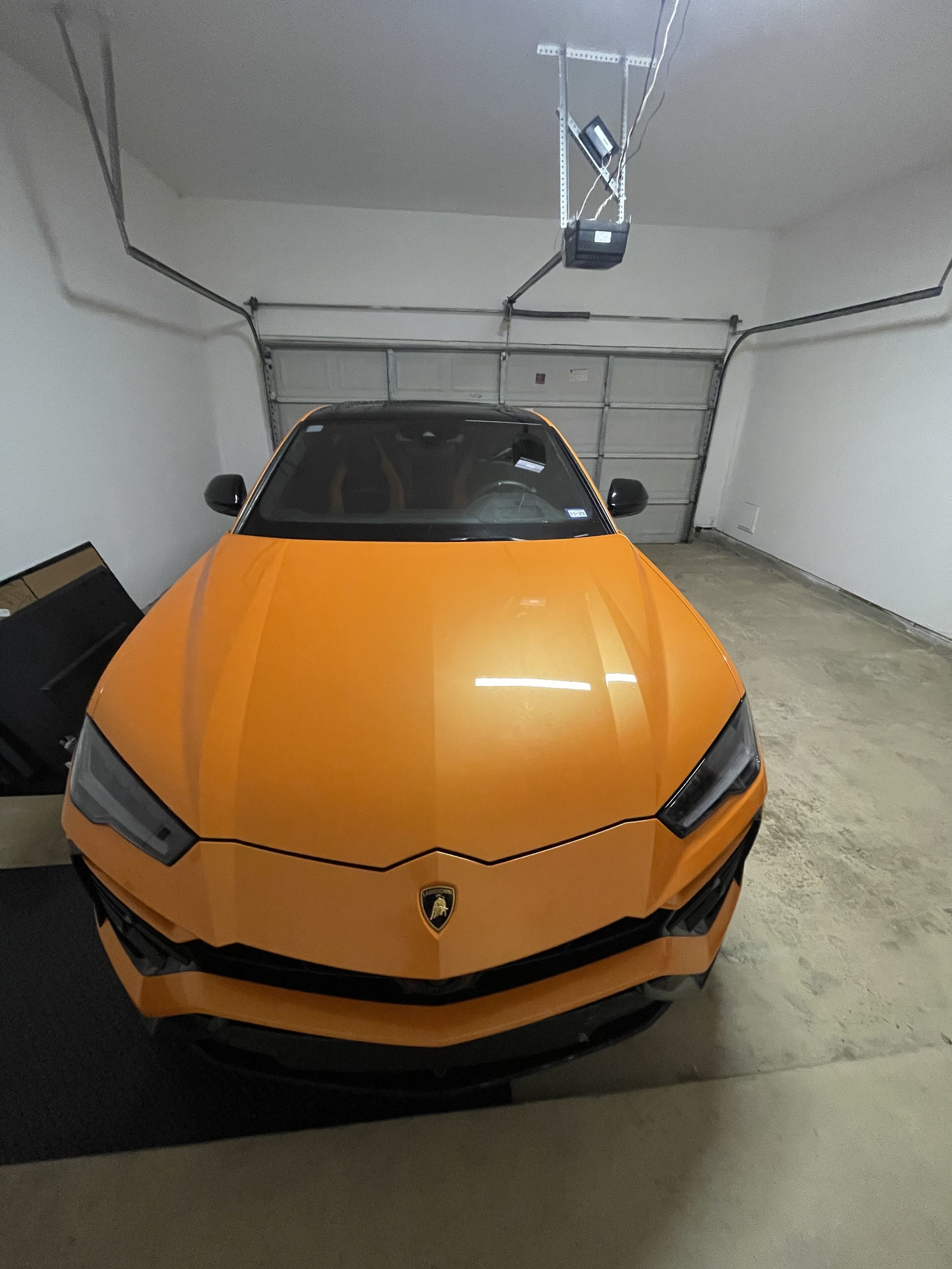 A Lamborghini parked in a garage with a concrete floor and white walls.