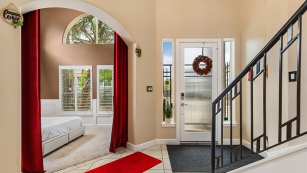 A hotel entrance with a red carpet, a staircase, and a door with a wreath.