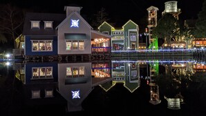 A waterfront property with multiple buildings, including a prominent house with a lit star symbol on the roof, a green building with a sign, and a tower with a sign reading "Baytown Wharf". - "Bay Watch" - AWESOME Condo with a water view and golf cart! (Miramar Beach)