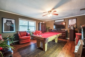 A pool room with a pool table, red chairs, a ceiling fan, and a television. - Mini Resort In SA, 3 Master Suites w Heated Pool, big screen & outdoor kitchen (San Antonio)