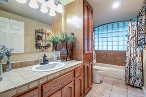 A bathroom with a wooden vanity, a sink, a toilet, and a bathtub. - Mini Resort In SA, 3 Master Suites w Heated Pool, big screen & outdoor kitchen (San Antonio)