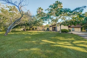 A residential property with a well-maintained lawn, a house with a tiled roof, and a small garden area. - Mini Resort In SA, 3 Master Suites w Heated Pool, big screen & outdoor kitchen (San Antonio)