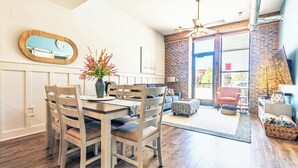 A dining area with a wooden table and chairs, a vase with flowers, and a wall-mounted mirror.