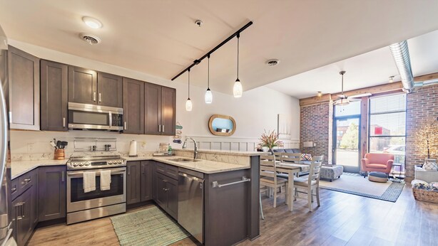 A modern kitchen with stainless steel appliances, a central island, and pendant lighting.