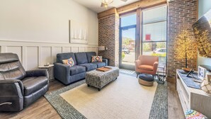 A modern living room with a leather recliner, a grey sofa, and a wooden coffee table.