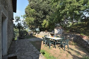 An outdoor dining area with stone walls, a stone pathway, and a table set for four with chairs.
