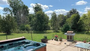 A hot tub with a wooden deck, a barbecue grill, and outdoor seating.
