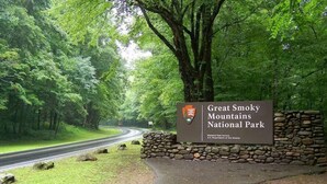 Un panneau indiquant l’entrée du parc national des Great Smoky Mountains, avec un mur de pierres et un chemin pavé.