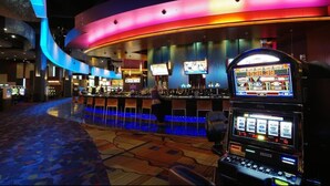 Un casino doté de machines à sous, d’un bar et d’un plafond incurvé agrémenté d’un éclairage coloré.