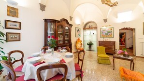 A dining area with a table set for four, a wooden cabinet, and a yellow armchair. - The paintress home with private patio (Firenze)