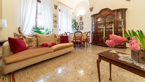 A living room with a sofa, chairs, a wooden cabinet, and a table with a vase of flowers. - The paintress home with private patio (Firenze)
