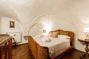 Un dormitorio con una cama de madera, una silla, una mesita y un radiador.