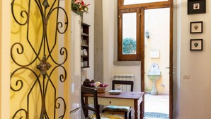 A dining area with a table, chairs, a decorative metal gate, a bookshelf, and a view through a doorway. - The paintress home with private patio (Firenze)