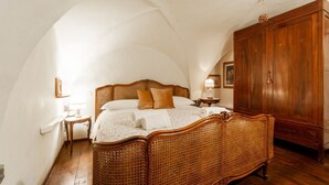 A bedroom with a wooden bed, a wooden wardrobe, and a small bedside table. - The paintress home with private patio (Firenze)