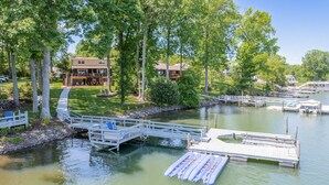 A lakeside property with a dock, inflatable rafts, and a pathway leading to a building. - Sunny Daze by SoCharm | Hot Tub | Fire Pit | Dock | Great Views (Denver)