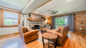 A cozy living room with a stone fireplace, leather sofas, and a wooden ceiling. - Sunny Daze by SoCharm | Hot Tub | Fire Pit | Dock | Great Views (Denver)
