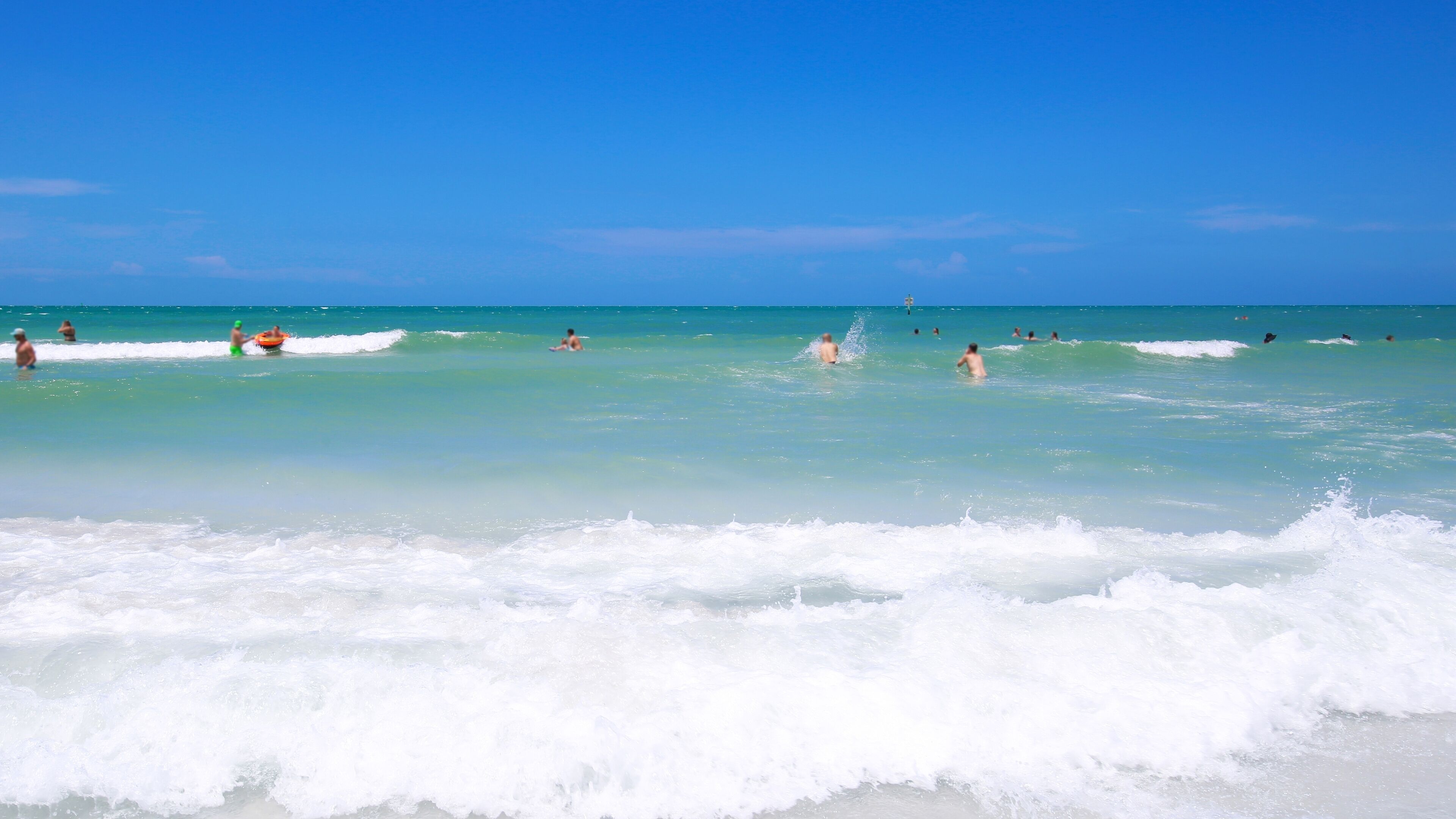 A beach with clear turquoise water and waves.