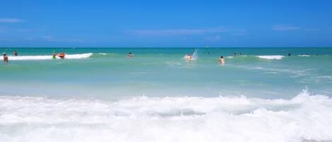 A beach with clear turquoise water and waves.