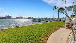 A waterfront view with a grassy area, a dock, and a marina in the background. - 🌴 Bayview Beauty @ Coral Resort | Waterfront • Pool • Dock • Walk to Beach ➠ CR B5 (Clearwater Beach)