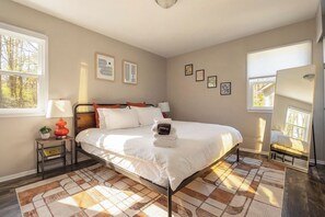 A bedroom with a bed, bedside tables, a mirror, framed pictures, and a window. - Sunny Spring Escape – Downtown 9 Min – Pool Tab – Relax N Raleigh (Raleigh)