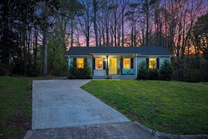 A single-story house with a front porch, a driveway, and a yard. - Sunny Spring Escape – Downtown 9 Min – Pool Tab – Relax N Raleigh (Raleigh)