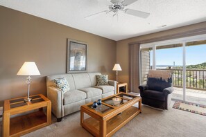 A living room with a sofa, two side tables with lamps, a coffee table, and a balcony with a view. - Beautiful Lake View Condo, Newly Updated & Ideally Located (Branson)